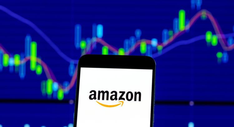 Amazon logo on smartphone with stock market chart showing price movements in background