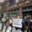 Protesters outside Tesla showroom with anti-Musk signs