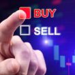 Close-up of a person's hand selecting the "BUY" option in red over the "SELL" option in white