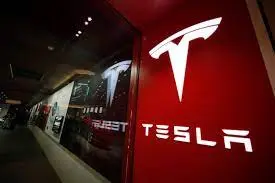Tesla logo display on red wall in retail store