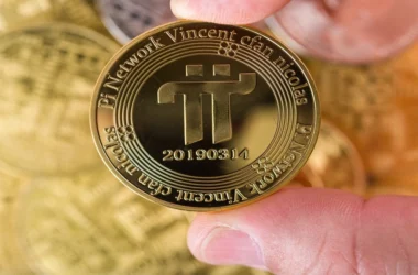 Physical Pi coin held between fingers showing the Pi symbol and network details