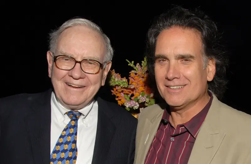 Warren Buffett smiling alongside his son Peter Buffett at an event