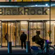 BlackRock headquarters entrance with illuminated company logo and person cycling past