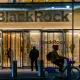 BlackRock headquarters entrance with illuminated company logo and person cycling past