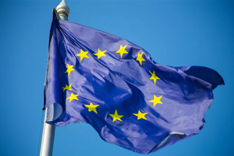 EU flag with yellow stars waving against blue sky