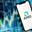 Smartphone displaying AMD logo with stock chart background