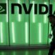 Nvidia logo illuminated in green light with person walking past