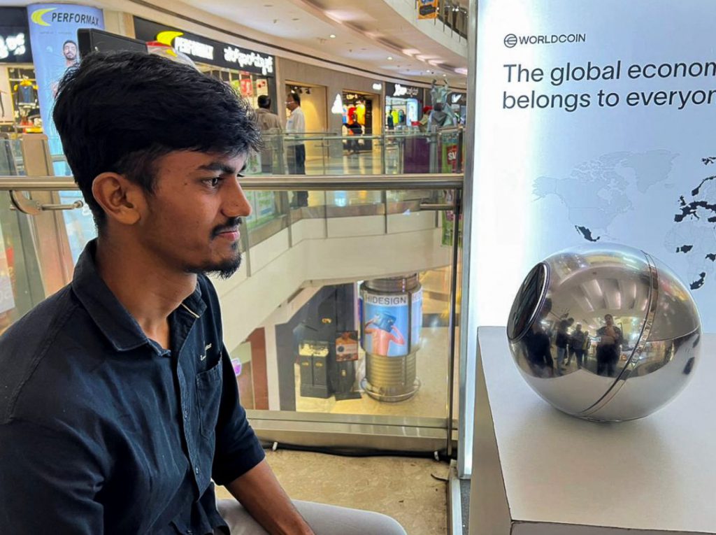 Man signs up for WorldCoin by having his eyes scanned by the spherical device in India