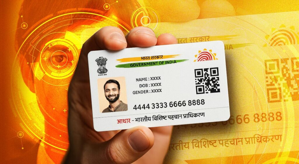 Hand holding Aadhaar card showing 12-digit identification number and Government of India biometric ID system